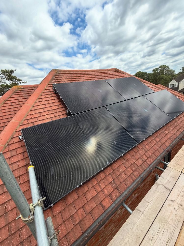 Black solar panels installed on a red tiled hip roof