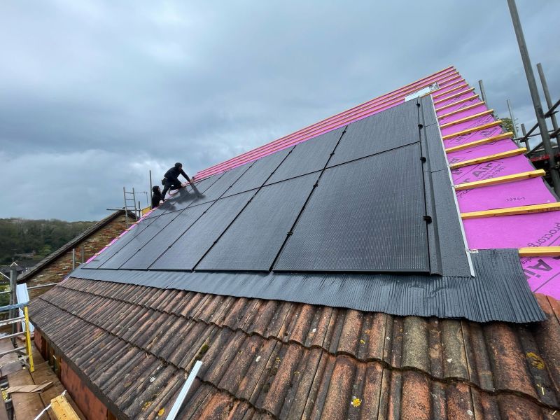 SF Mann installers fitting black solar panels on a pitched roof